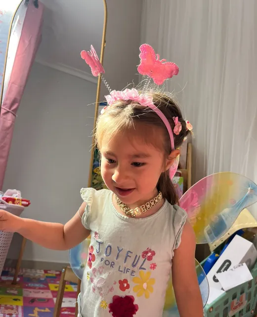 Niña sonriendo con cintillo de mariposa