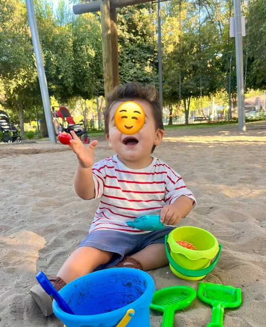 Niño jugando con baldes en el arenero