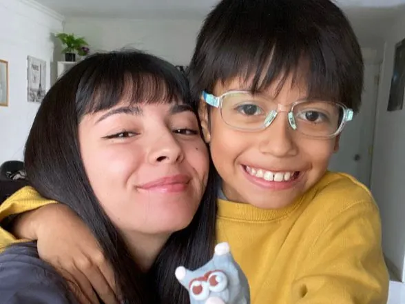 Profesional de Un Cuidado Integral abrazando a un niño que muestra una figura de plasticina