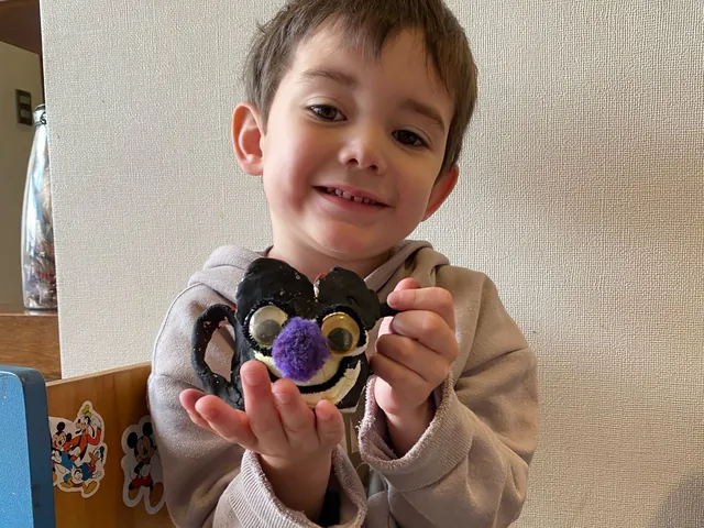 Niño sonriendo mientras muestra su juguete
